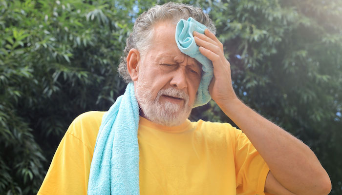Older man wiping sweat during summer