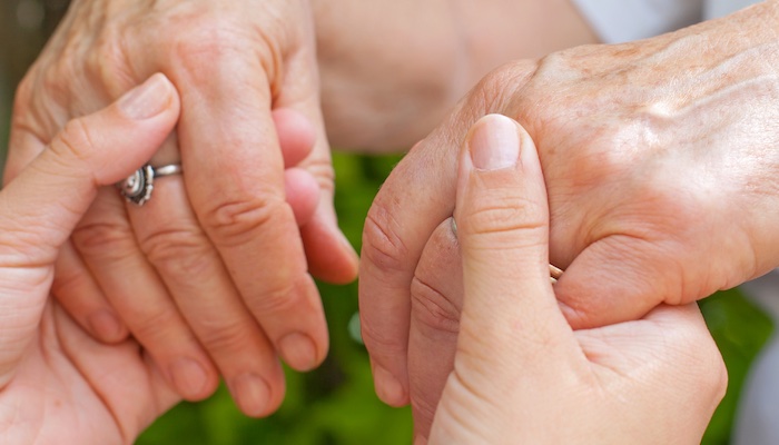 Two older adults hold hands