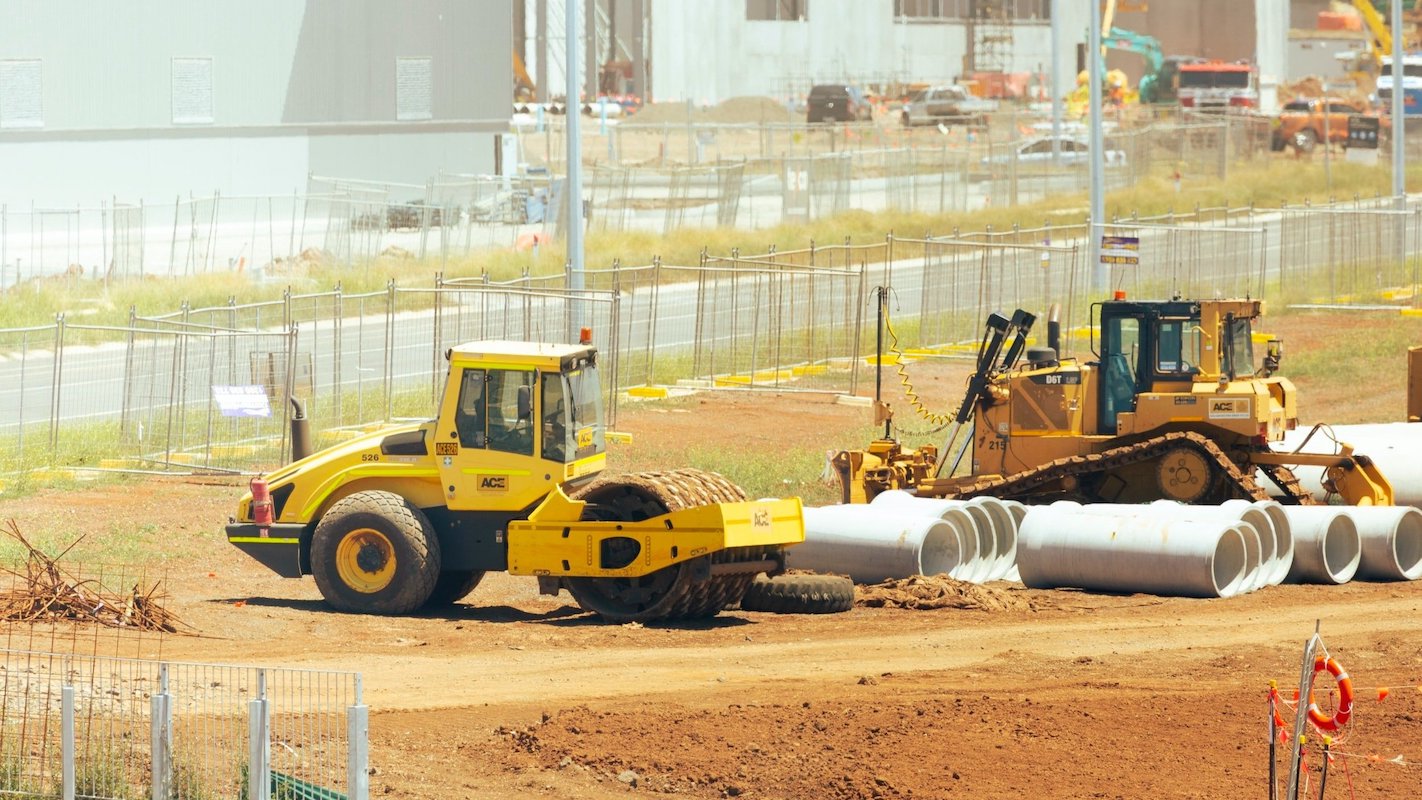 Heavy duty construction vehicles and pipes on dirt plot