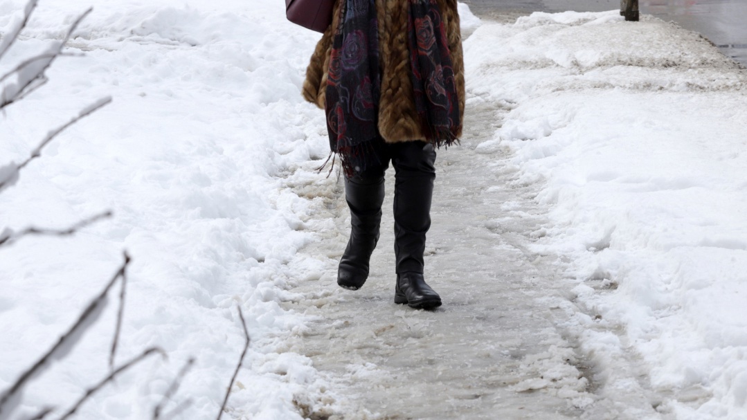 An image of a woman walking cautiously in the snow, demonstrating safe steps to prevent falls during winter. 