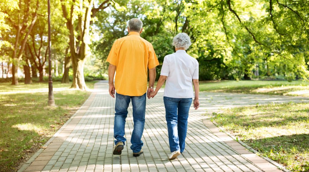 Older couple walks down park path