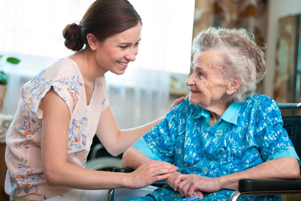Caregiver puts her hand on the shoulder of older adult woman