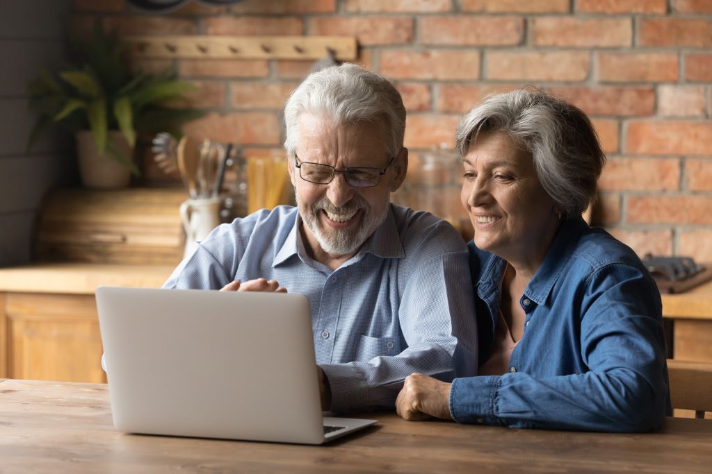 Older adult couple look at Medicare help on a laptop