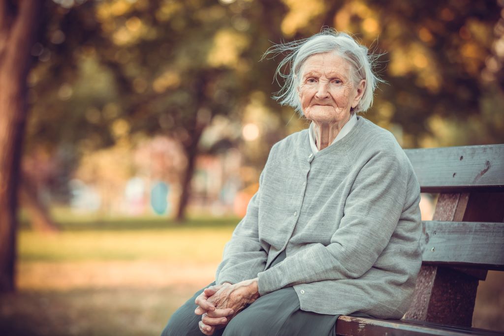 Lost older woman sits on bench