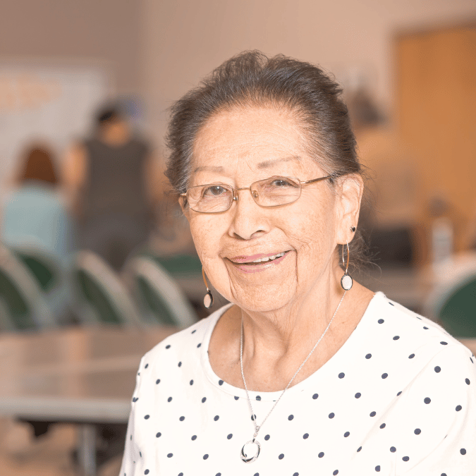 Senior woman in white shirt with polka dots smiling at the camera