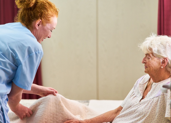 Nurse helping older woman with covers