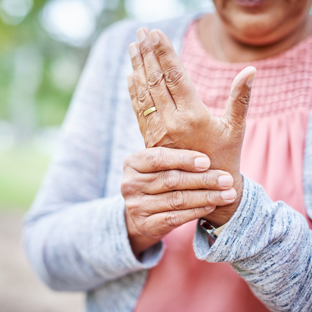 Older woman clutching her hand, likely from arthritis pain and discomfort. 