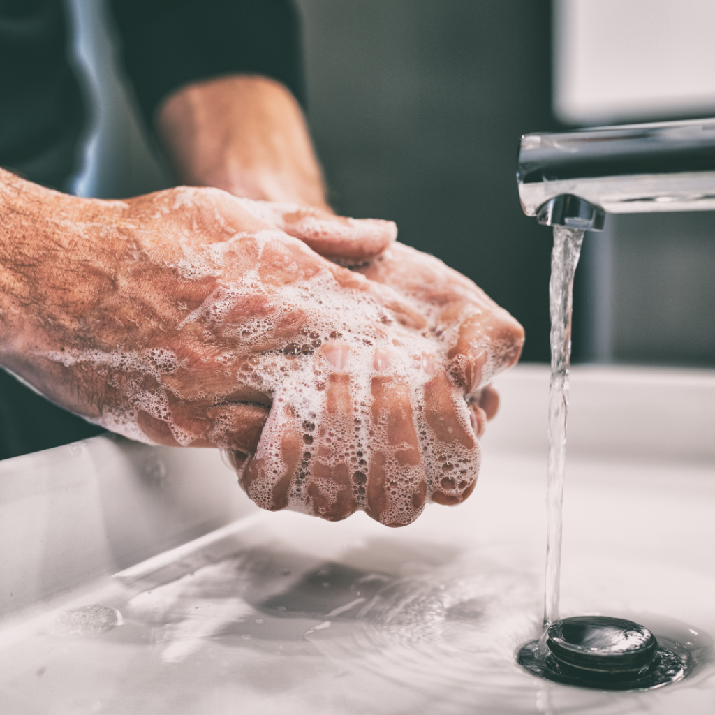 up close shot of the hands of an older white male being washed in the sink