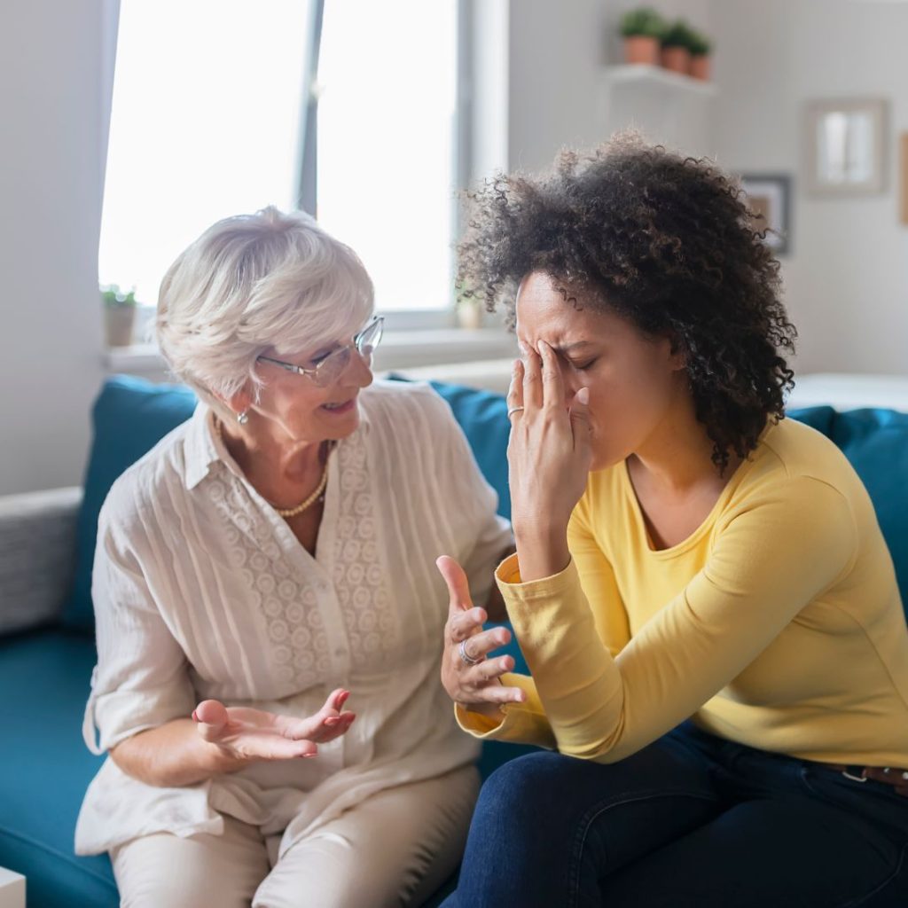 An older woman is talking to a visibly upset younger woman on a blue couch.