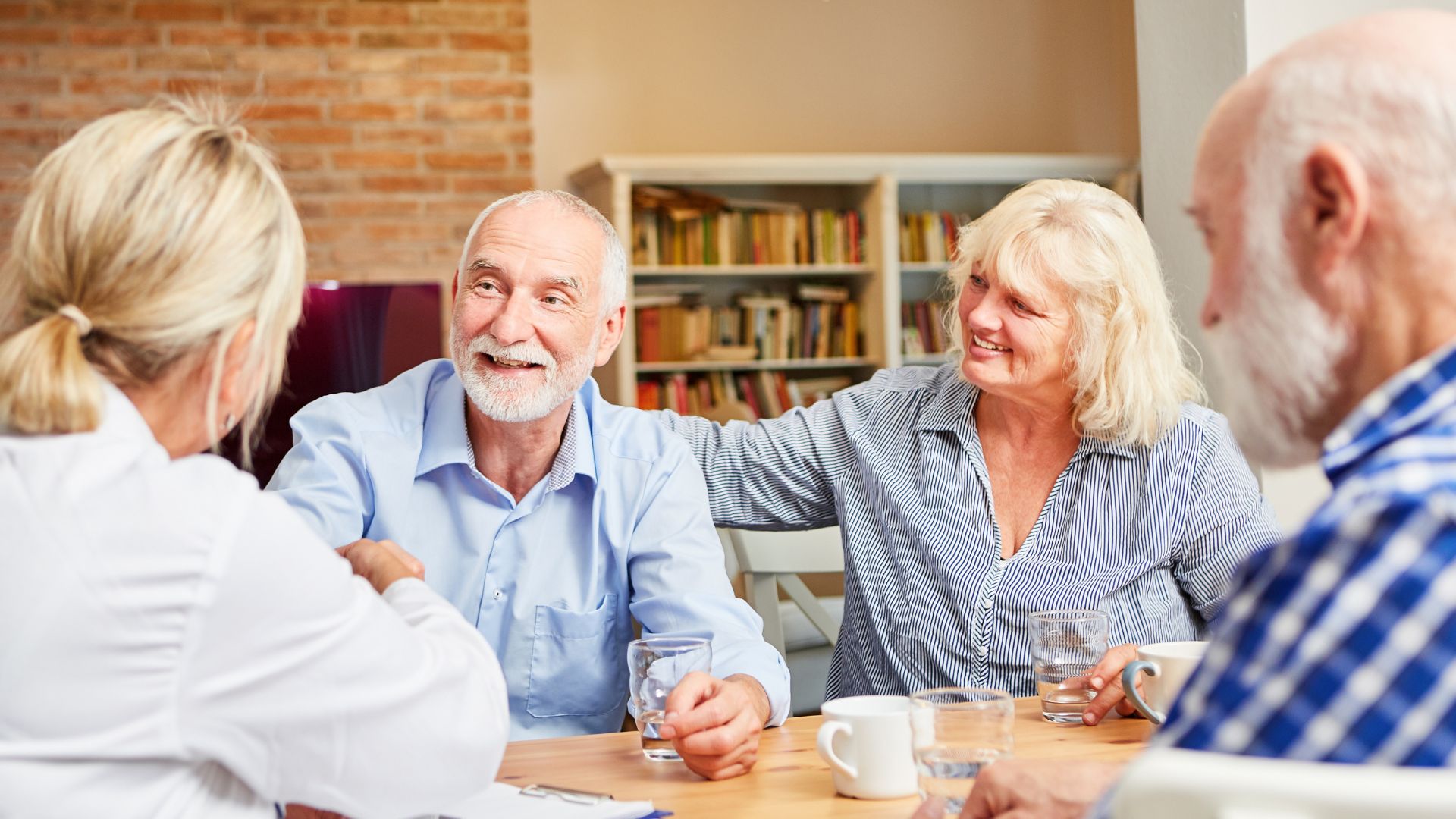 Older Adults and a care provider having a discussion at a table.