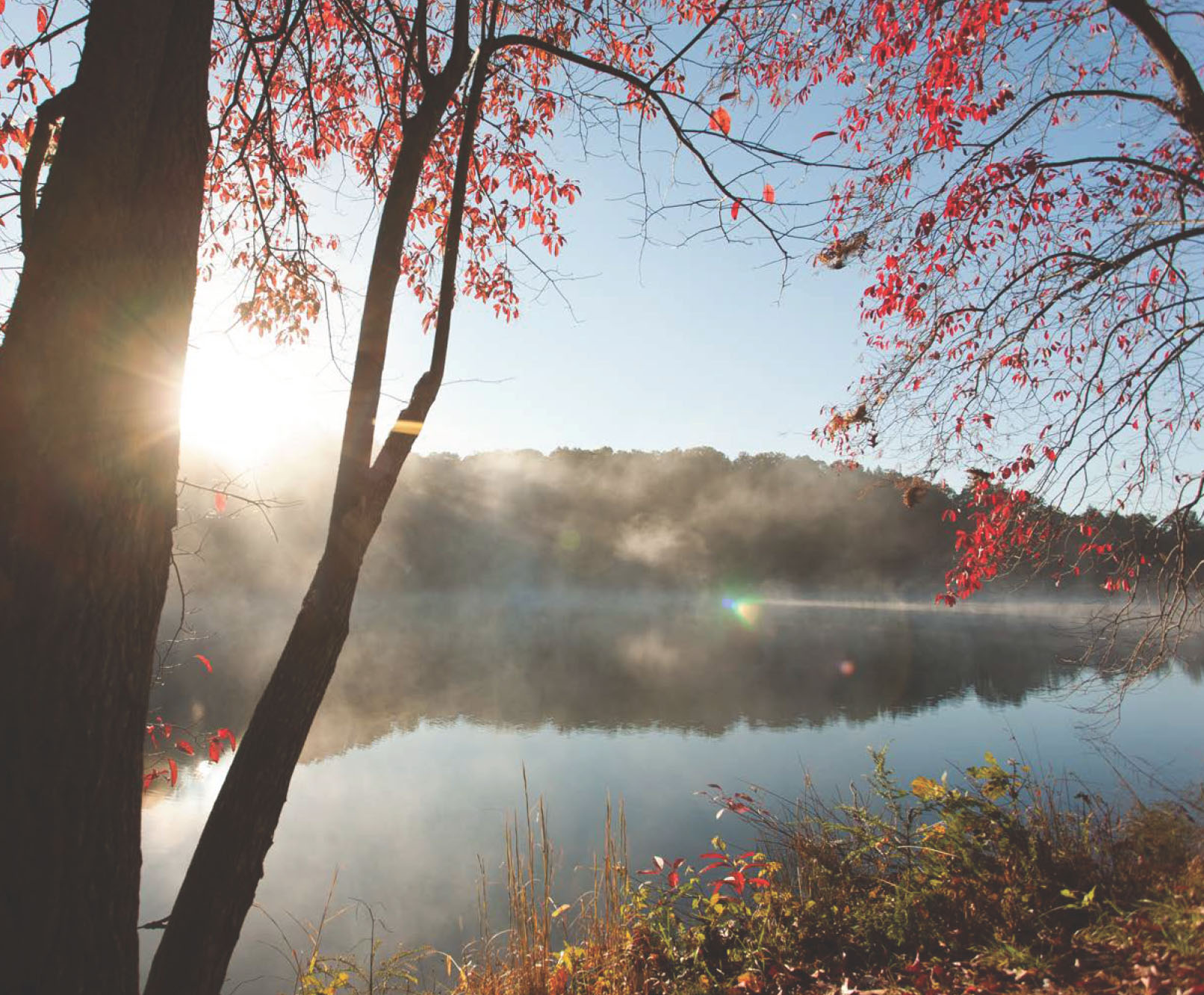 Fog over a lake with the sun rising over a ridge