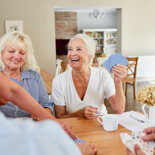 A group of older adults laughing and playing a card game