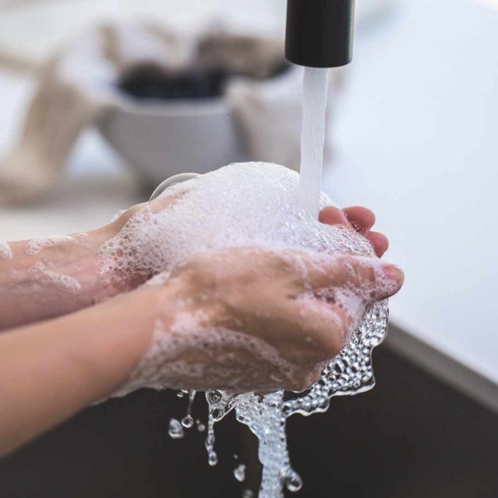 Hands being thoroughly washed with soap under running water.
