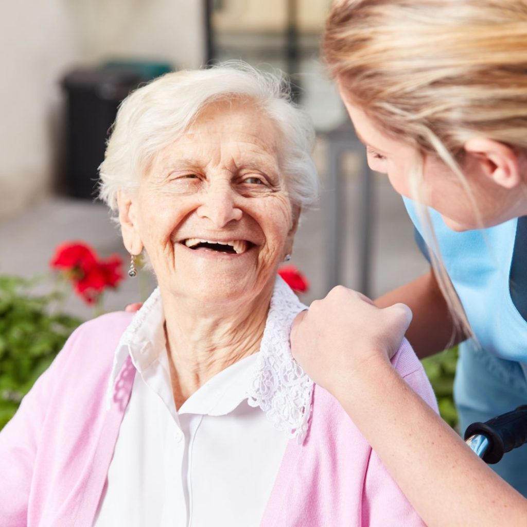 Smiling older woman with caregiver offering support outdoors