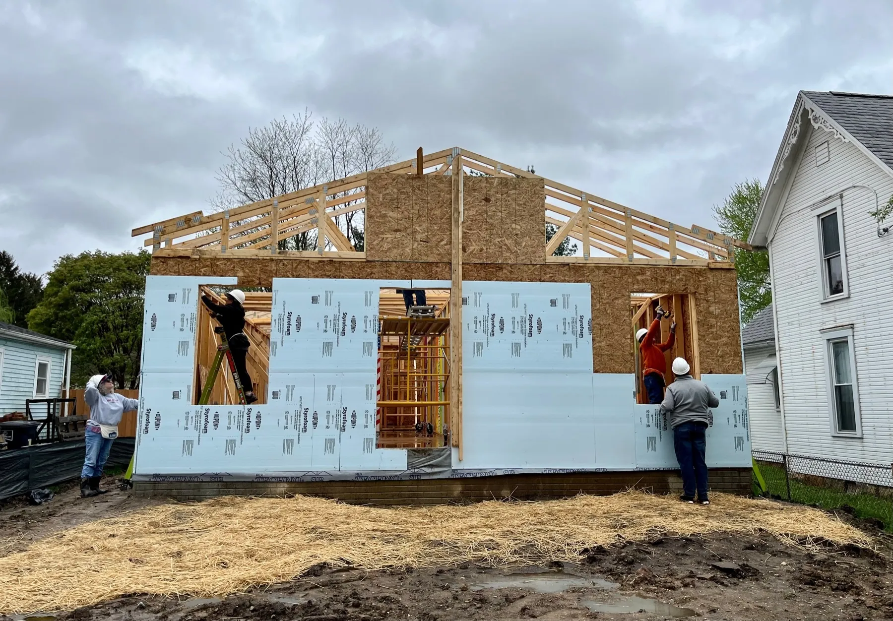 Volunteers and tradespeople work on a Habitat for Humanity home construction site.