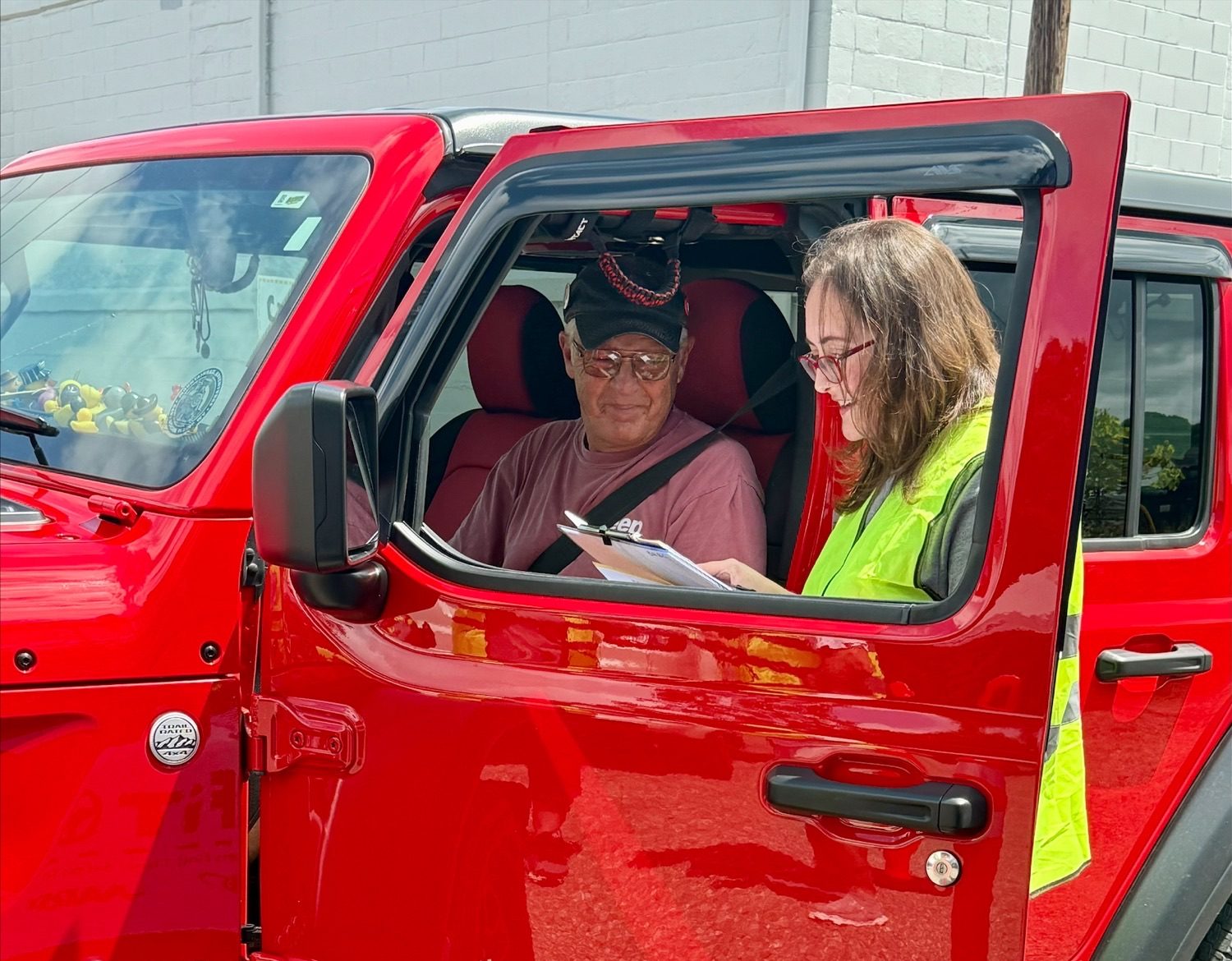 A CarFit volunteer with checklist in hand speaks with a driver.