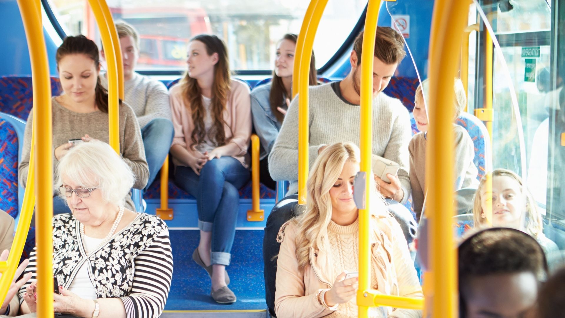 Several individuals aboard a transit bus on a sunny day.