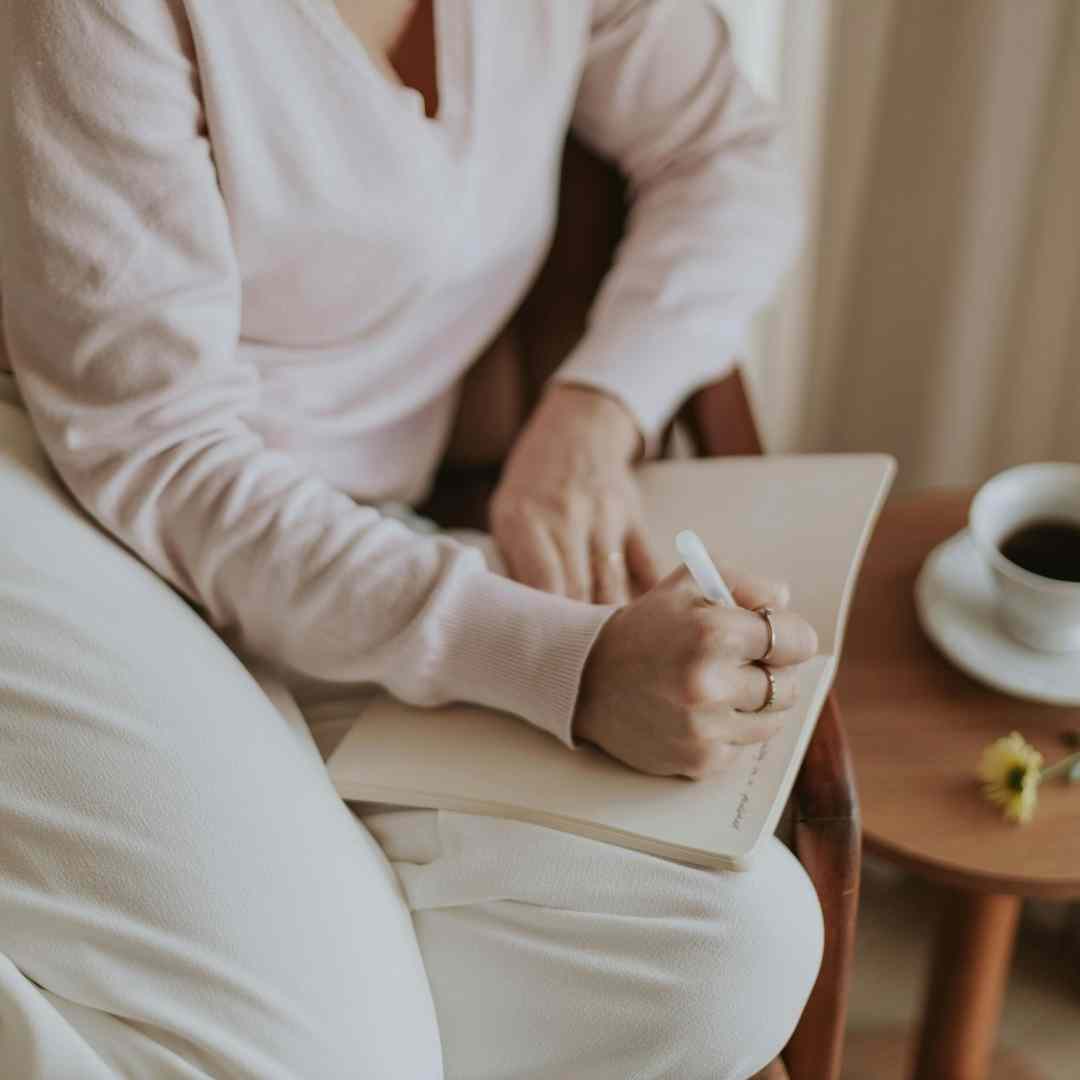 A woman sitting in a chair writing in a journal