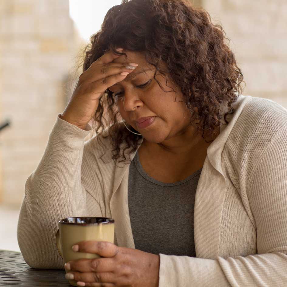 A woman holding a mug seems deep in thought.