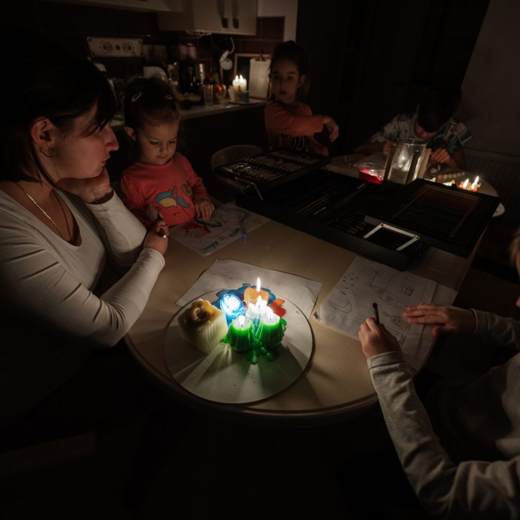 Family gathered around a table using candles and flashlights during a power outage.