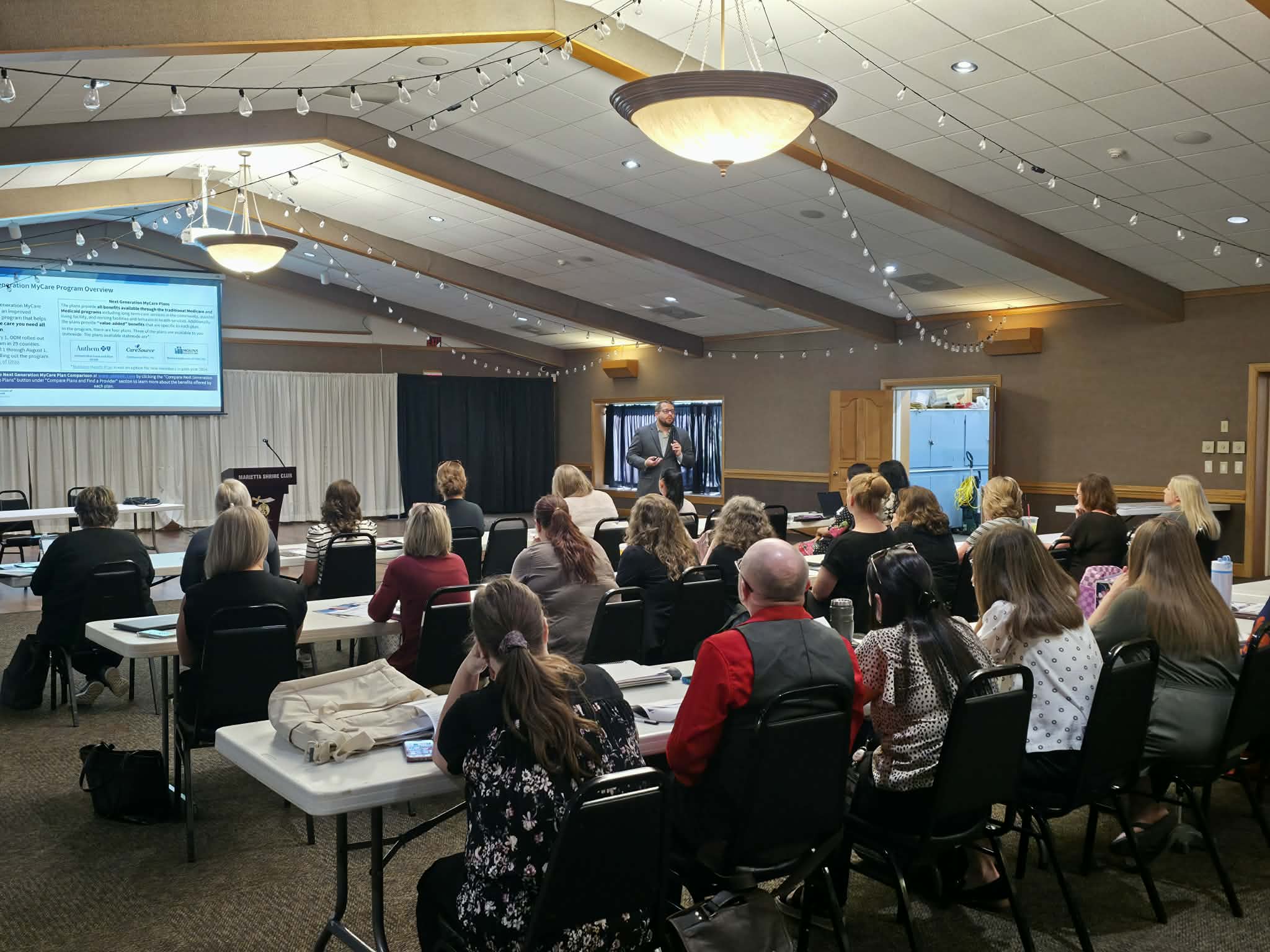Room full of people with speaker at the front giving a presentation