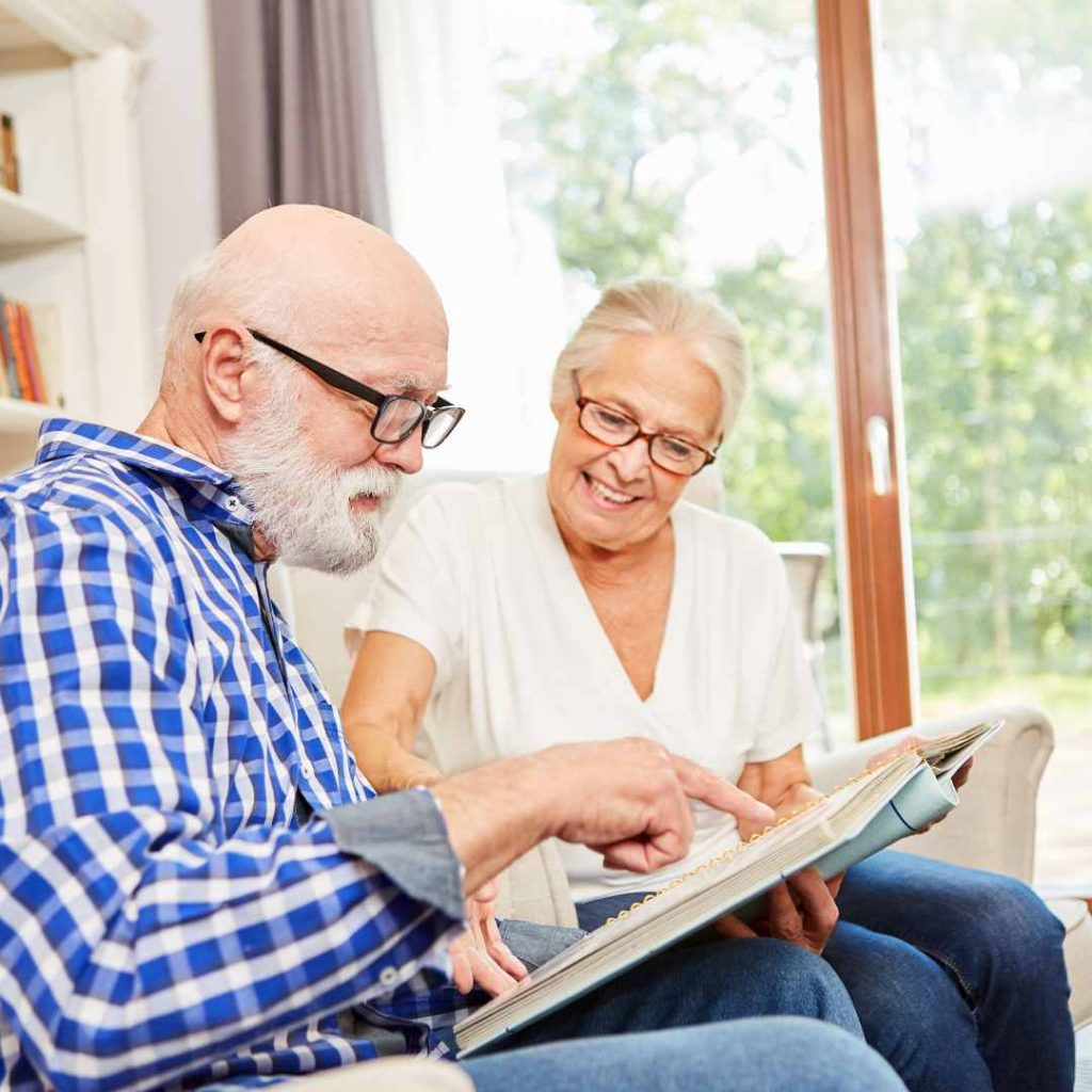 Older couple sitting together and looking through a photo album.