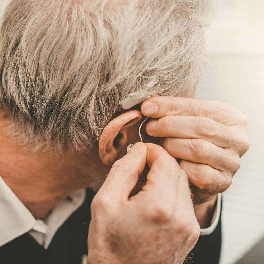 Close-up of an older adult adjusting their hearing aid