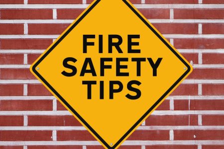 Large diamond shape sign against brick wall that reads "Fire Safety Tips"