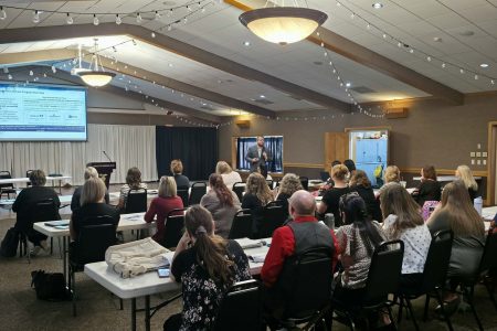 Room full of people with speaker at the front giving a presentation