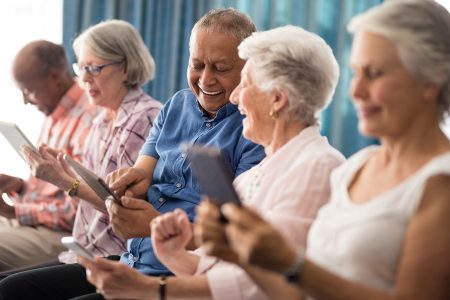 Older adults laugh and smile as they use tablets together