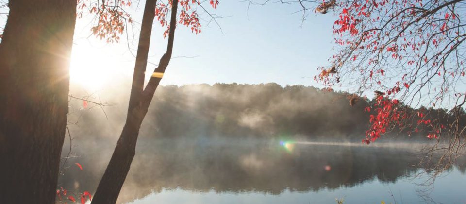 Fog over a lake with the sun rising over a ridge