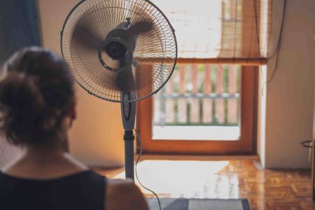 View of the back of a woman's head with a fan blowing in front of her