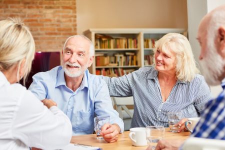 Older Adults and a care provider having a discussion at a table.