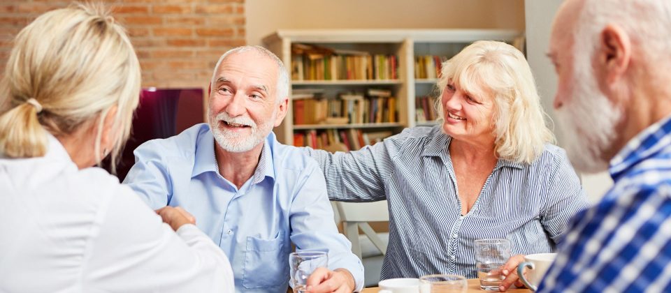 Older Adults and a care provider having a discussion at a table.