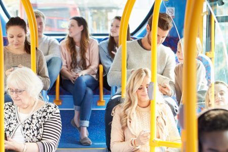Several individuals aboard a transit bus on a sunny day.