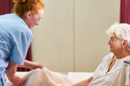 Nurse helping older woman with covers